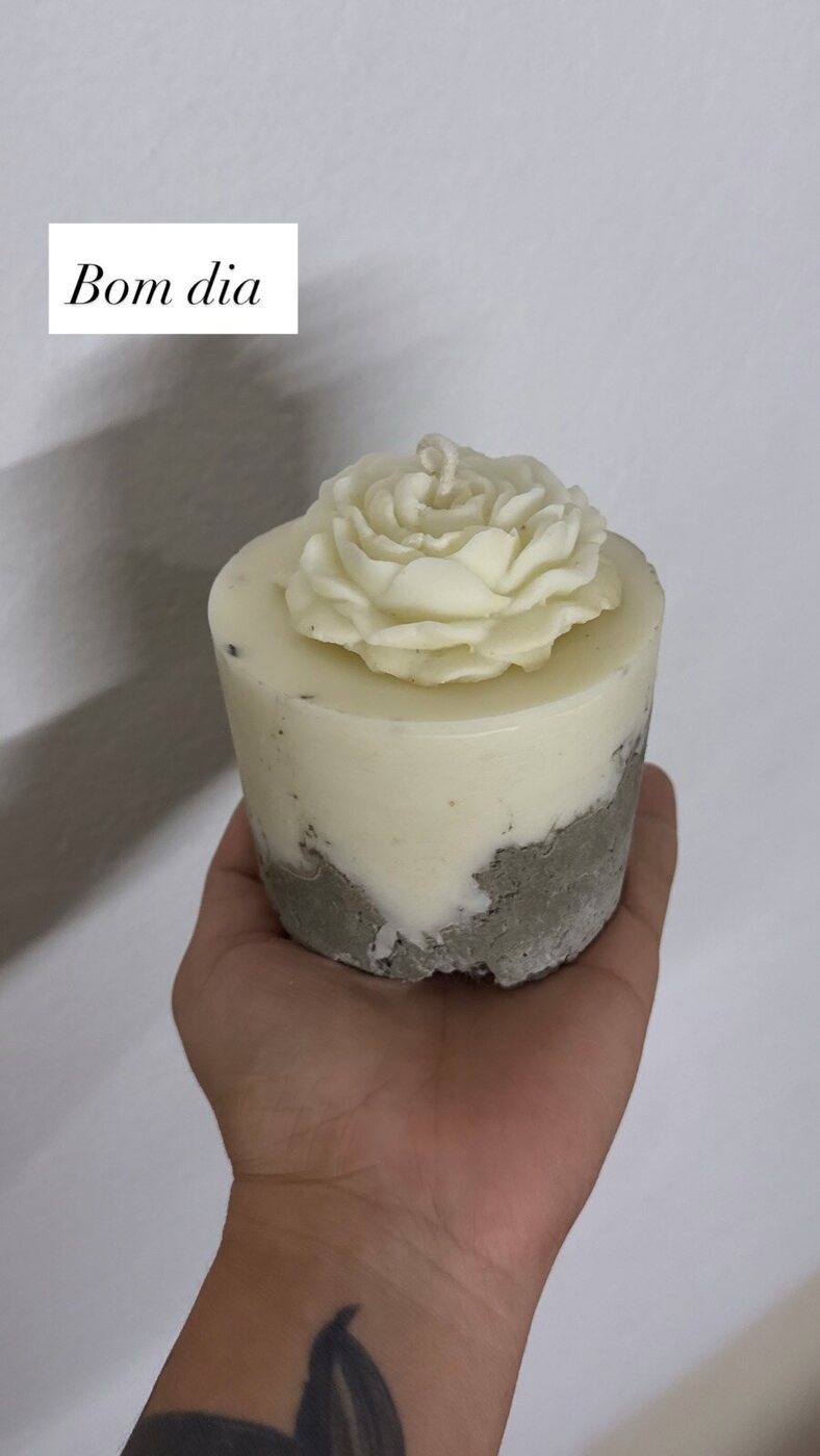 Vela de concreto com flor, na mão
